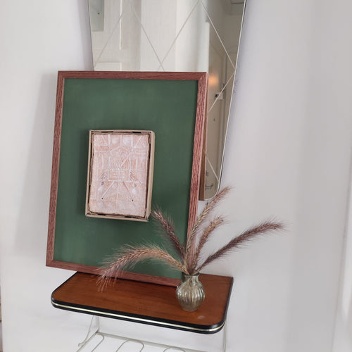 Small wooden shelf with a framed picture and vase against a white wall